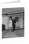 Mature couple walking on sidewalk front of house by Anonymous