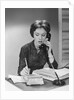 Brunette business woman sitting desk talking telephone writing note on calendar by Anonymous