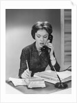 Brunette business woman sitting desk talking telephone writing note on calendar by Anonymous