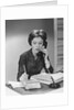 Brunette business woman sitting desk talking telephone writing note on calendar by Anonymous