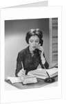 Brunette business woman sitting desk talking telephone writing note on calendar by Anonymous