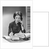 Brunette business woman sitting desk talking telephone writing note on calendar by Anonymous