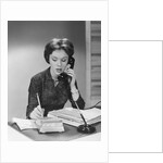Brunette business woman sitting desk talking telephone writing note on calendar by Anonymous
