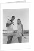 Portrait tennis couple man woman holding racquets standing by net by Anonymous