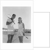 Portrait tennis couple man woman holding racquets standing by net by Anonymous