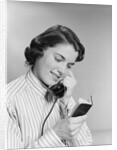 Young woman talking on telephone reading address from little black book by Anonymous