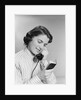 Young woman talking on telephone reading address from little black book by Anonymous