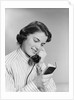 Young woman talking on telephone reading address from little black book by Anonymous