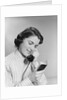 Young woman talking on telephone reading address from little black book by Anonymous