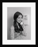 Smiling teenage girl talking on rotary wall telephone by Anonymous
