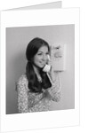 Smiling teenage girl talking on rotary wall telephone by Anonymous