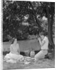 Teenage couple picnic boy taking photograph of girl outdoors by Anonymous