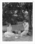 Teenage couple picnic boy taking photograph of girl outdoors by Anonymous