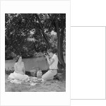 Teenage couple picnic boy taking photograph of girl outdoors by Anonymous