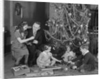 Family christmas photo father two daughters and son with presents and tree by Anonymous