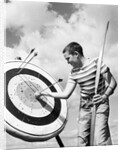 Boy jeans striped t-shirt holding bow & pulling arrow out of target bull's-eye by Anonymous
