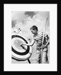 Boy jeans striped t-shirt holding bow & pulling arrow out of target bull's-eye by Anonymous