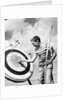 Boy jeans striped t-shirt holding bow & pulling arrow out of target bull's-eye by Anonymous