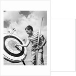 Boy jeans striped t-shirt holding bow & pulling arrow out of target bull's-eye by Anonymous