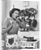 Housewife tasting with spoon by stove funny facial expression by Anonymous