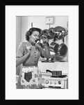 Housewife tasting with spoon by stove funny facial expression by Anonymous