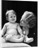 Blond woman mother smiling looking at baby sitting on pillow by Anonymous