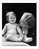 Blond woman mother smiling looking at baby sitting on pillow by Anonymous