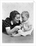 Woman mother smiling sitting playing with baby daughter by Anonymous
