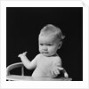 Baby in high chair making shrugging gesture by Anonymous
