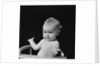 Baby in high chair making shrugging gesture by Anonymous