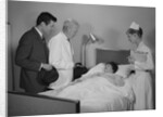 Doctor nurse husband talking with female patient in hospital bed by Anonymous