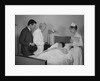 Doctor nurse husband talking with female patient in hospital bed by Anonymous