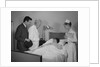 Doctor nurse husband talking with female patient in hospital bed by Anonymous