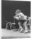 Toddler sitting in chair pouring milk from bottle into bowl for puppy dog by Anonymous