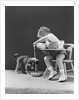 Toddler sitting in chair pouring milk from bottle into bowl for puppy dog by Anonymous