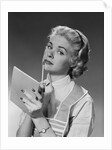 Blond woman wearing apron writing pad in hand pencil to chin thinking by Anonymous