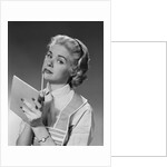 Blond woman wearing apron writing pad in hand pencil to chin thinking by Anonymous