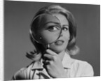 Blond woman magnifying glass held up to and enlarging one eye by Anonymous