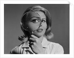 Blond woman magnifying glass held up to and enlarging one eye by Anonymous