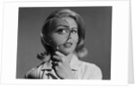 Blond woman magnifying glass held up to and enlarging one eye by Anonymous