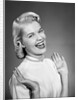 Woman wearing pearls smiling with hands up thumbs tucked under arm by Anonymous