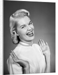 Woman wearing pearls smiling with hands up thumbs tucked under arm by Anonymous