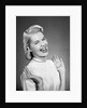 Woman wearing pearls smiling with hands up thumbs tucked under arm by Anonymous