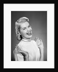 Woman wearing pearls smiling with hands up thumbs tucked under arm by Anonymous
