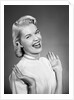 Woman wearing pearls smiling with hands up thumbs tucked under arm by Anonymous