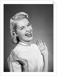 Woman wearing pearls smiling with hands up thumbs tucked under arm by Anonymous