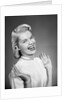 Woman wearing pearls smiling with hands up thumbs tucked under arm by Anonymous