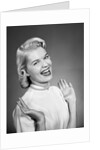 Woman wearing pearls smiling with hands up thumbs tucked under arm by Anonymous
