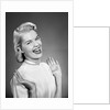 Woman wearing pearls smiling with hands up thumbs tucked under arm by Anonymous