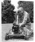 Elderly man in yard kneeling down to fix lawnmower by Anonymous